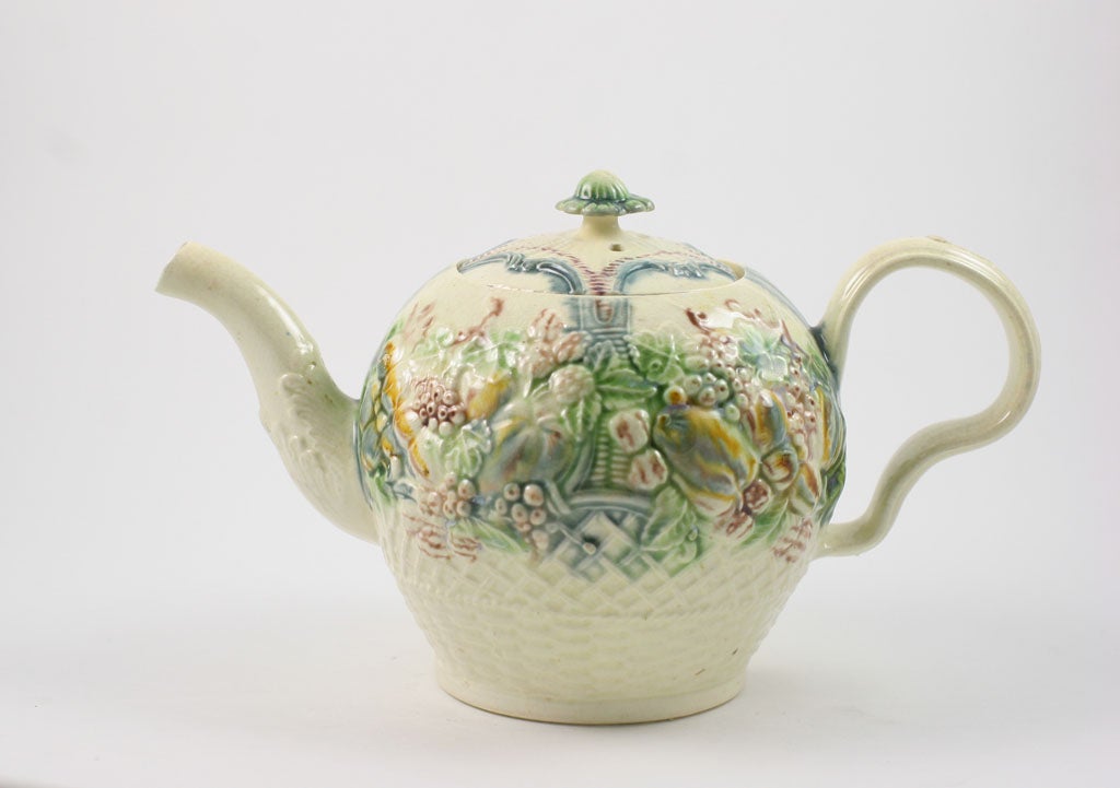 A fine William Greatbatch creamware teapot molded with raised fruit and shells over a basket weave lower section, decorated in underglaze oxide colors